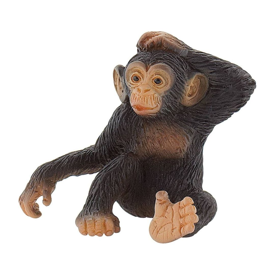 Handmålad figur av en liten schimpansunge i sittande pose, med naturtrogna detaljer och mörkbrun päls.